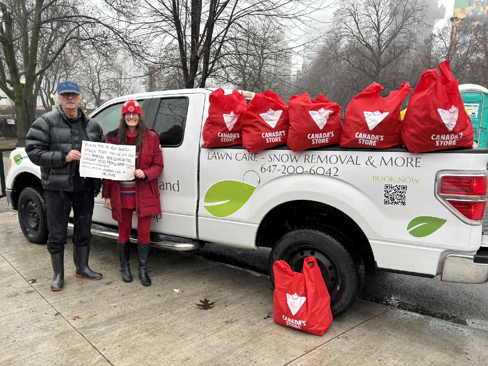 Adriana Violo and Mr. Mike beside a pickup truck loaded with red donation bags for the annual Christmas Care Pack Drive in Toronto