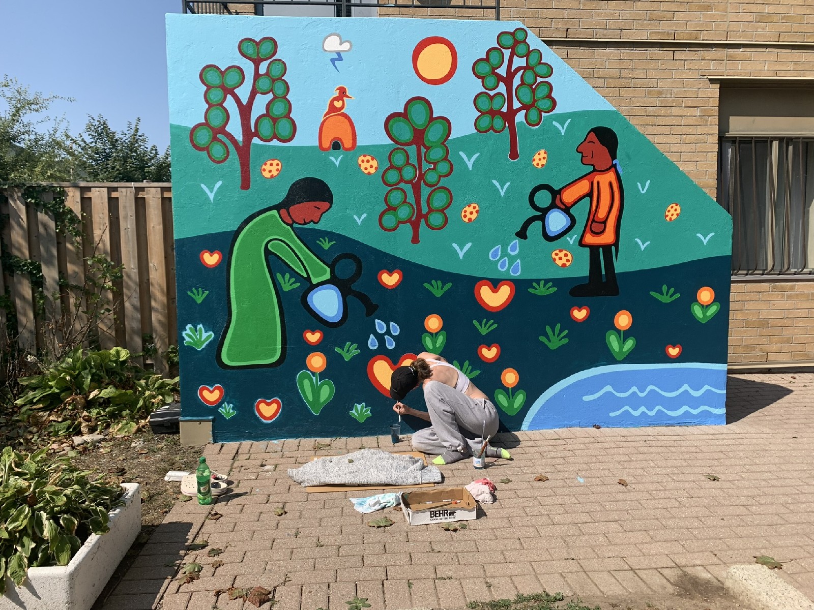 A community mural being painted in Toronto featuring Indigenous-inspired figures tending gardens